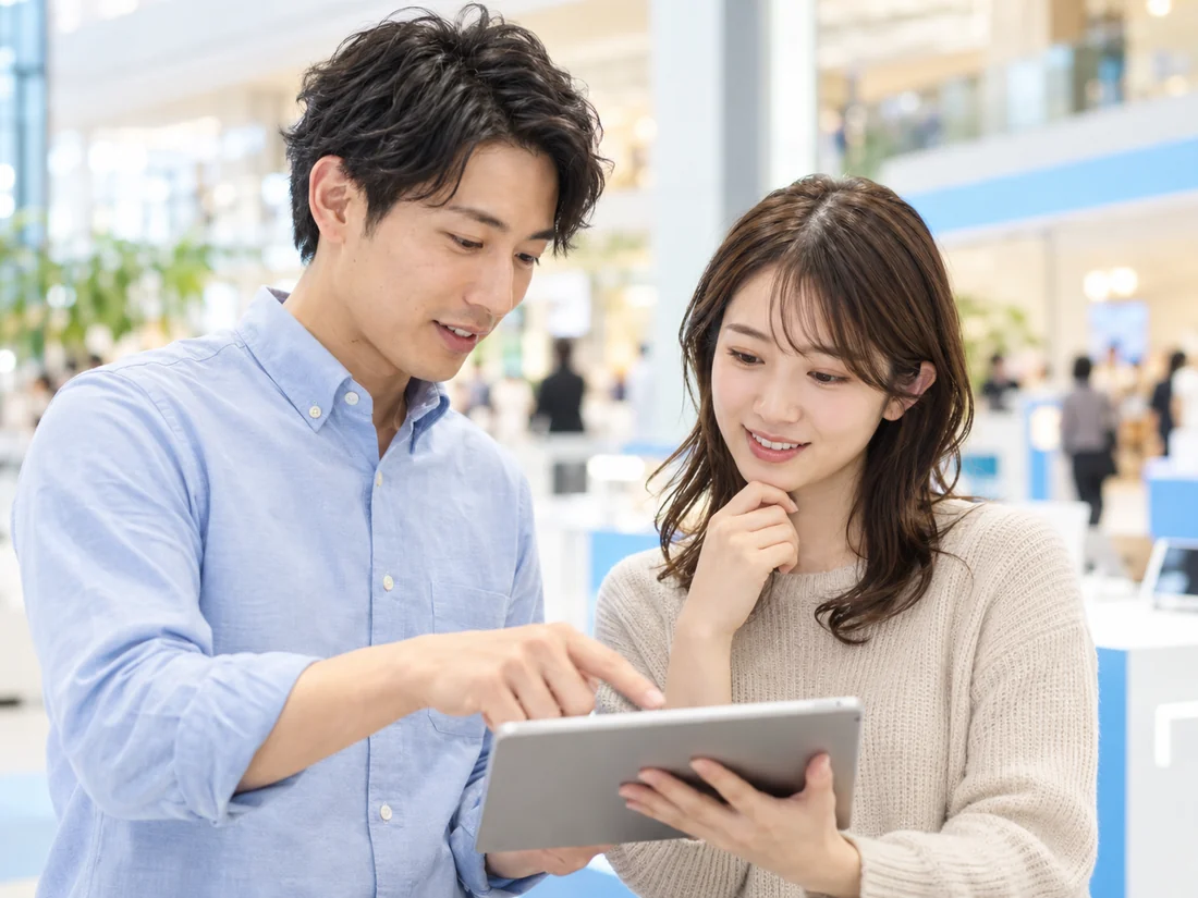 タブレットを見ながら相談する二人の架空の成人スタッフ