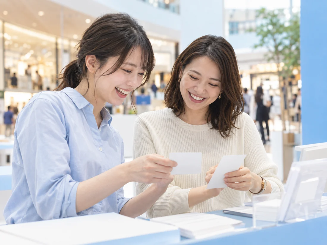 メモを確認しながら自然に笑い合う二人の架空の成人スタッフ
