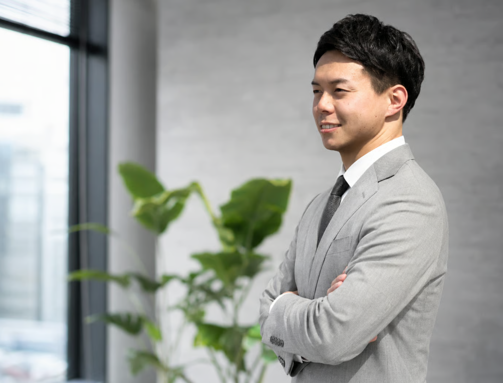 左を向き、腕を組む西川達也代表